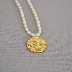Macro shot of freshwater rice pearls with a golden sunburst coin pendant necklace