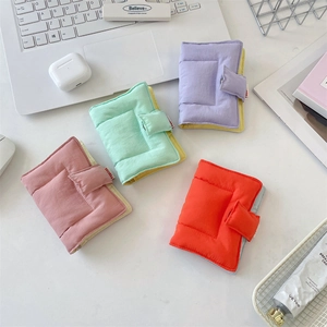 Detailed view of quilted fabric card holders in pink, green, orange, and purple on a desk