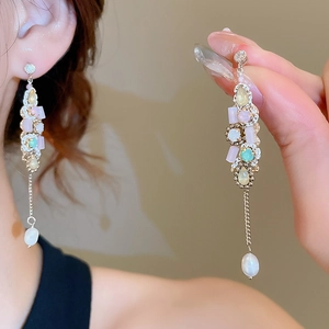 Close-up of tassel earrings with colorful stones and elegant hanging white pearl droplets