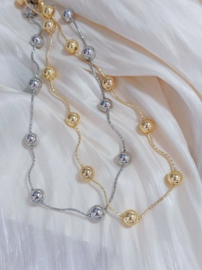 Detail of 18k gold and silver plated beaded choker necklaces on white silk fabric