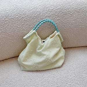 Detail of light green floral embroidered canvas tote bag with woven blue rope handles