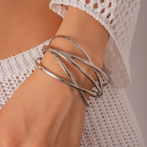 Close-up of minimalist layered silver bangle with geometric crossover design on wrist