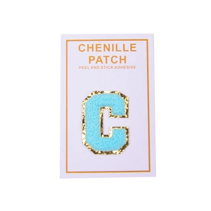 Detail of light blue chenille letter C patch with gold sequins and peel-off adhesive