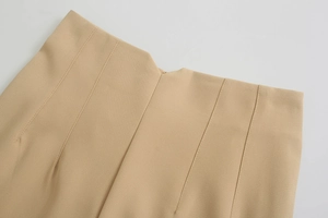 Dettaglio della vita alta con pinces e cuciture su pantaloni beige accorciati