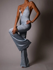 Close-up of light blue satin jumpsuit featuring open back and metal chain straps detail