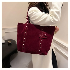 Detail of dark red suede tote bag with metallic rivets and a heart-shaped charm