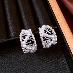 Detail of silver-plated C-shaped earrings with hand-wrapped pearls on black velvet