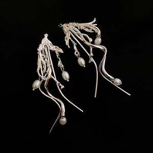 Macro detail of silver tassel earrings with irregular pearls over black texture