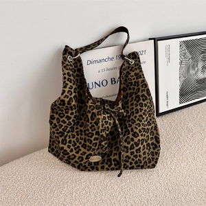 Close-up of leopard print canvas tote bag featuring knot straps and metal logo detail