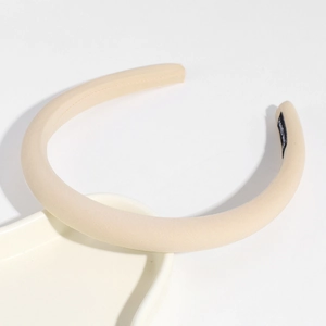 Detail of beige fabric headband featuring a black woven label with hand made text