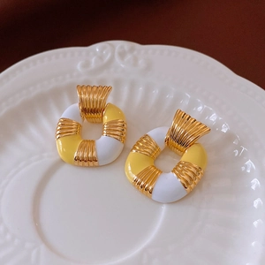 Detailed close-up of French-style gold square earrings on a decorative white dish