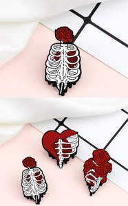 Detailed close-up of skull and rose enamel brooches in red, white and black alloy pins