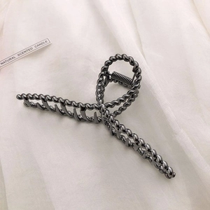 Macro detail of gunmetal grey hair claw clip with twisted texture on white fabric