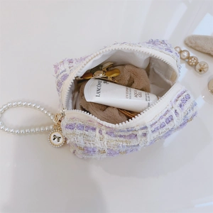 Detail of tweed mini bag featuring a pearl handle and bow charm with interior items