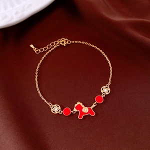 Détail du bracelet plaqué or avec cheval rouge et breloques sur tissu en soie marron
