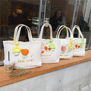 Quilted cotton tote bag with flower embroidery and plush keychain on outdoor ledge