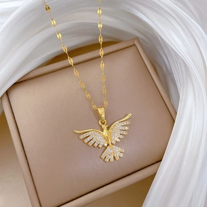 Macro view of gold phoenix pendant necklace with white zircons on silk background