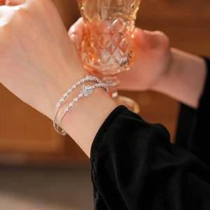 Gros plan d'un bracelet double couche argenté avec fleur en zircon porté par un mannequin