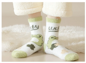 Close-up of white plush socks with green frog patterns and lucky text in mink velvet
