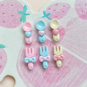 Close-up of pink, blue and yellow mini resin heart spoons and bow forks for DIY crafts