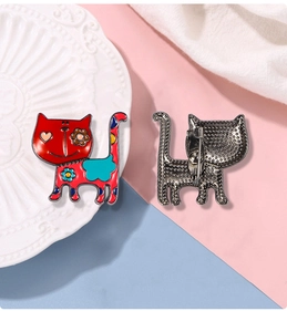 Detail showing red cartoon cat brooch with floral accents and pin clasp on back