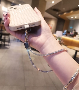 Detailed view of luxury rhinestone phone strap with silver clasp on wavy beige case
