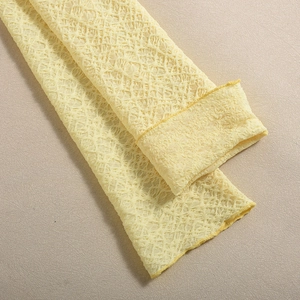 Gros plan de manches longues en dentelle jaune clair avec motif floral ajouré et couture