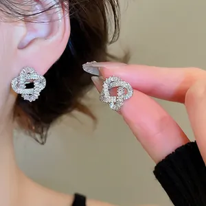 Silver needle stud earrings with gold plating and paved zircon crystals in a knot design