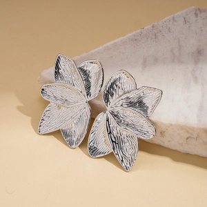 Macro shot of silver petal-shaped earrings with hammered metal texture on stone base