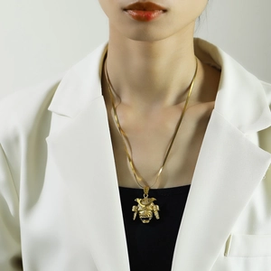 Detailed close-up of a golden warrior helmet pendant on a snake chain worn by a model