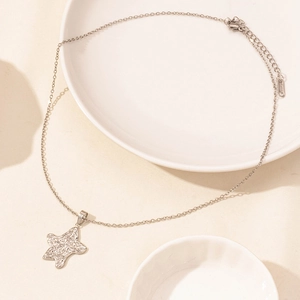 Macro detail of silver irregular starfish pendant on a delicate chain necklace