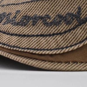 Macro view of khaki cotton twill fabric with black script embroidery and stitching