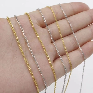 Hand holding assorted 18k gold and silver stainless steel cross chains with lobster clasps
