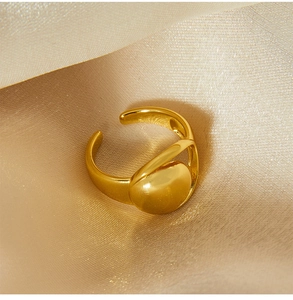 Detailed close-up of a gold geometric moon cutout ring on champagne silk fabric