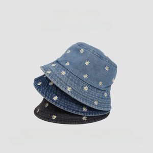 Detail of stacked denim bucket hats in light blue, dark blue, and black with daisy embroidery