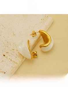 Detailed macro shot of gold plated teardrop earrings with white resin inlay on stone