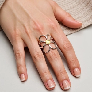 Chic hollow flower ring in silver with gold center accent on model finger