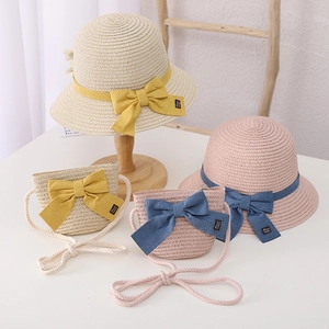Detail of straw hat and matching bow bag set for kids in beige and pink colors