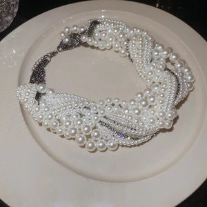 Chic multi-layer faux pearl and dark metal chain necklace on a ceramic plate