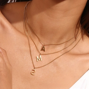 Close-up of triple-layered 18k gold chain necklace with A, M, S letter pendants