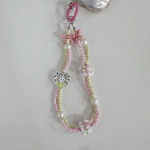 Detailed view of pink and beige beaded phone charm with heart flower and strawberry beads