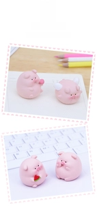 Close-up of cute pink resin pig figurines with wings and watermelon for desk decor