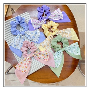 Flat lay of five colorful floral bow scrunchies with long ribbons on a wooden background