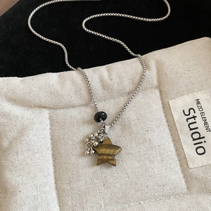 Macro shot of silver box chain necklace with a tiger eye textured star pendant