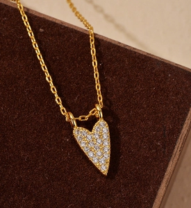 Close-up of gold-plated heart pendant with full diamond pavé on a brown velvet surface