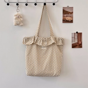 Close-up of cream canvas tote bag with black polka dots and ruffle edge detail