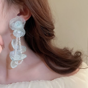 Gros plan de boucles d'oreilles fleurs en tulle bleu clair avec glands en cristal