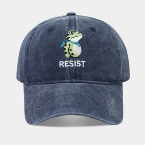 Detailed close-up of green frog embroidery and RESIST text on navy washed cotton cap