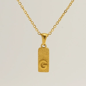 Macro shot of gold stainless steel necklace with sandblasted rectangle G letter pendant