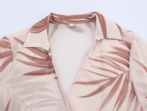 Detail of V-neck collar on chiffon blouse featuring brown tropical palm leaf print